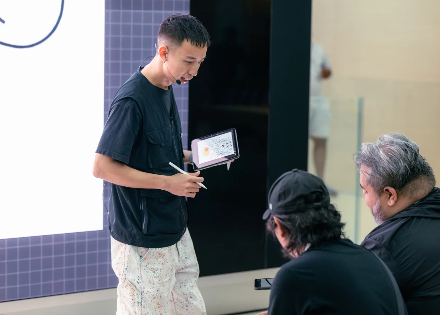 Cloakwork holds an iPad and stylus while speaking with workshop participants